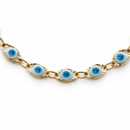 Gold bracelet with eye-shaped white and blue beads on a white background