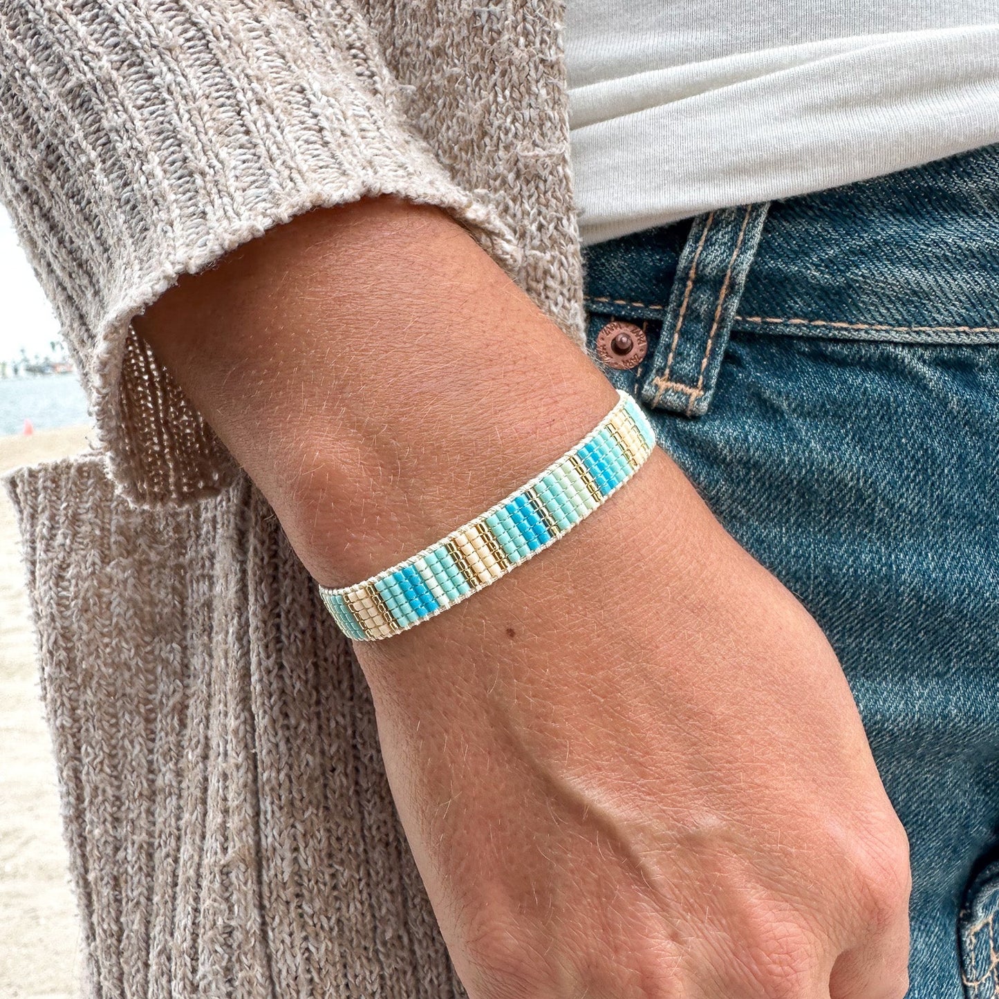 Person wearing a colorful beaded bracelet on a neutral background