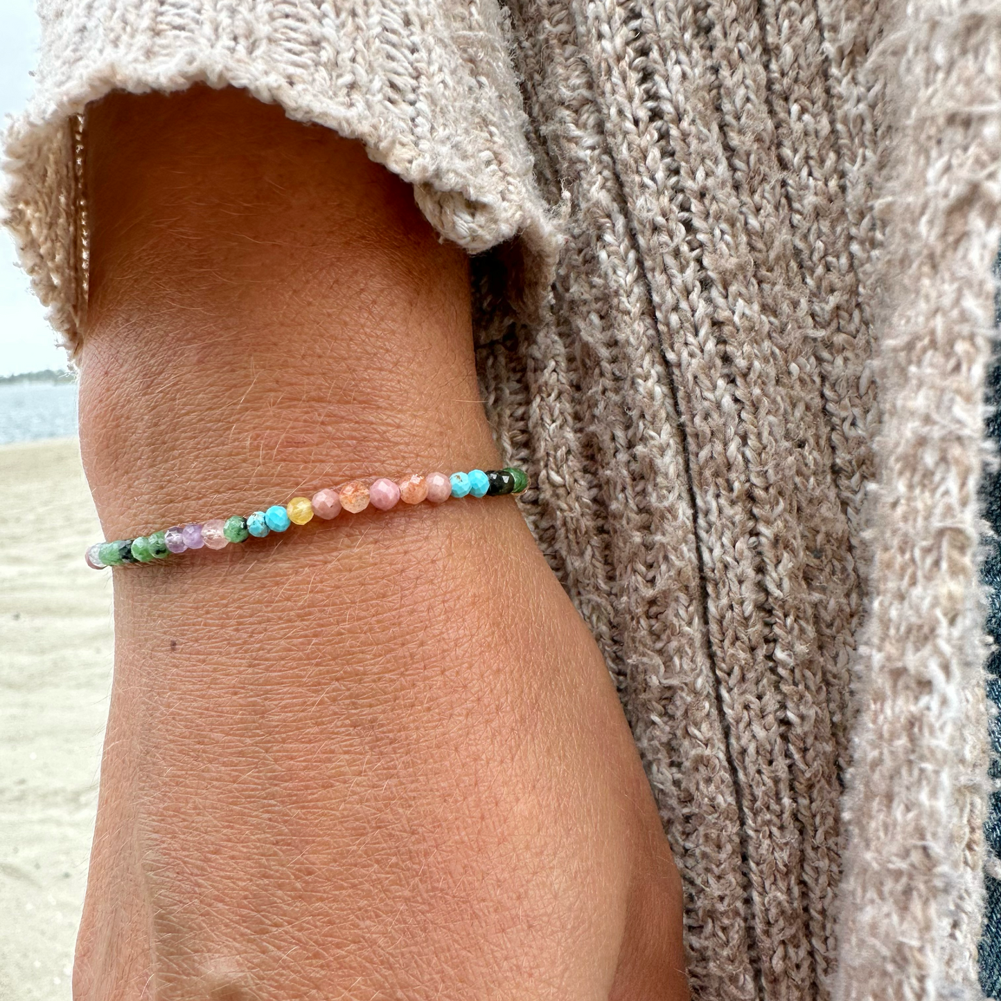 Close-up of a wrist wearing a colorful beaded bracelet with a neutral background.