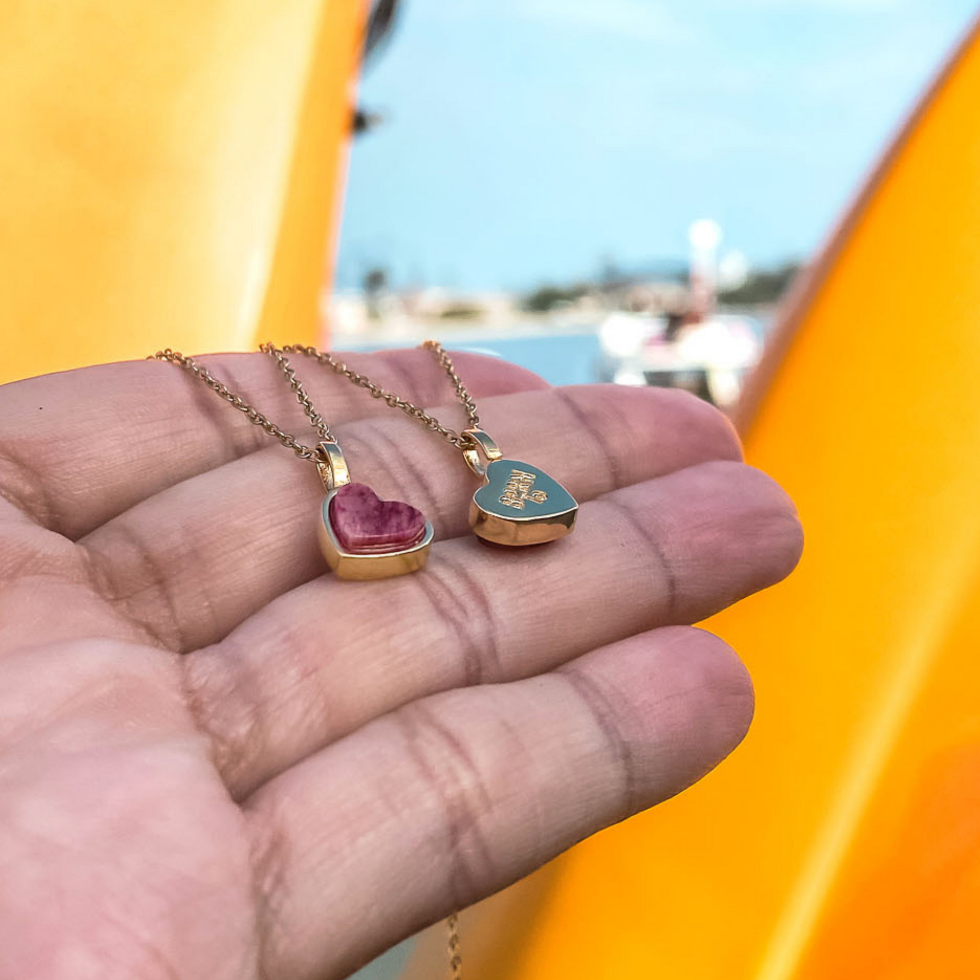 Yellow gold charm necklace with a heart shaped red feldspar natural gemstone. Made by Born to Rock. Online  jewelry store based in San Diego California