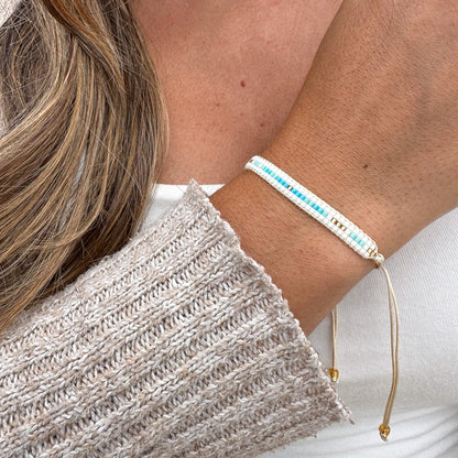 Close-up of a person wearing a bracelet with blue beads and gold accents.