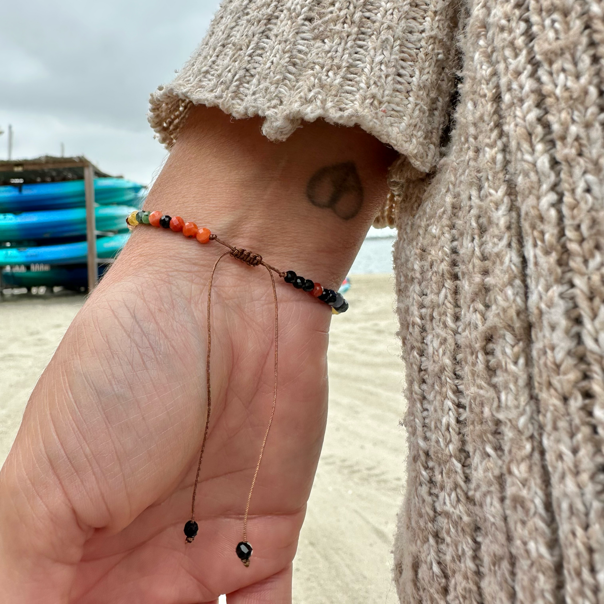 Hand wearing a bracelet with beads on a beach
